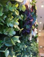 Close-up of an event stylist’s hand arranging muted olive green foliage on an elegant linen backdrop.