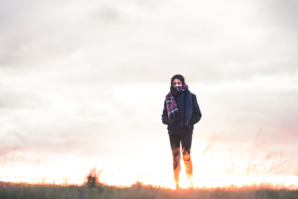 woman walking on green grass under cloudy sky at daytime