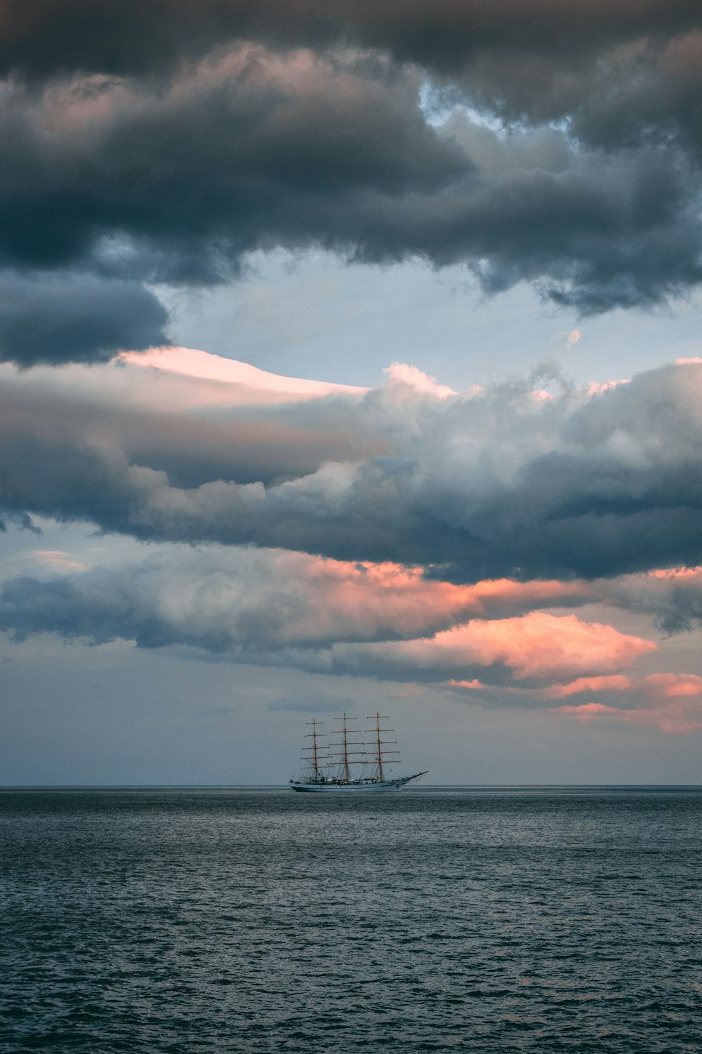 navire blanc et brun dans l’eau de l’océan sous un ciel nuageux pendant la journée