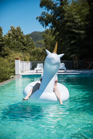A bright inflatable unicorn pool shimmering under the summer sun in a backyard.