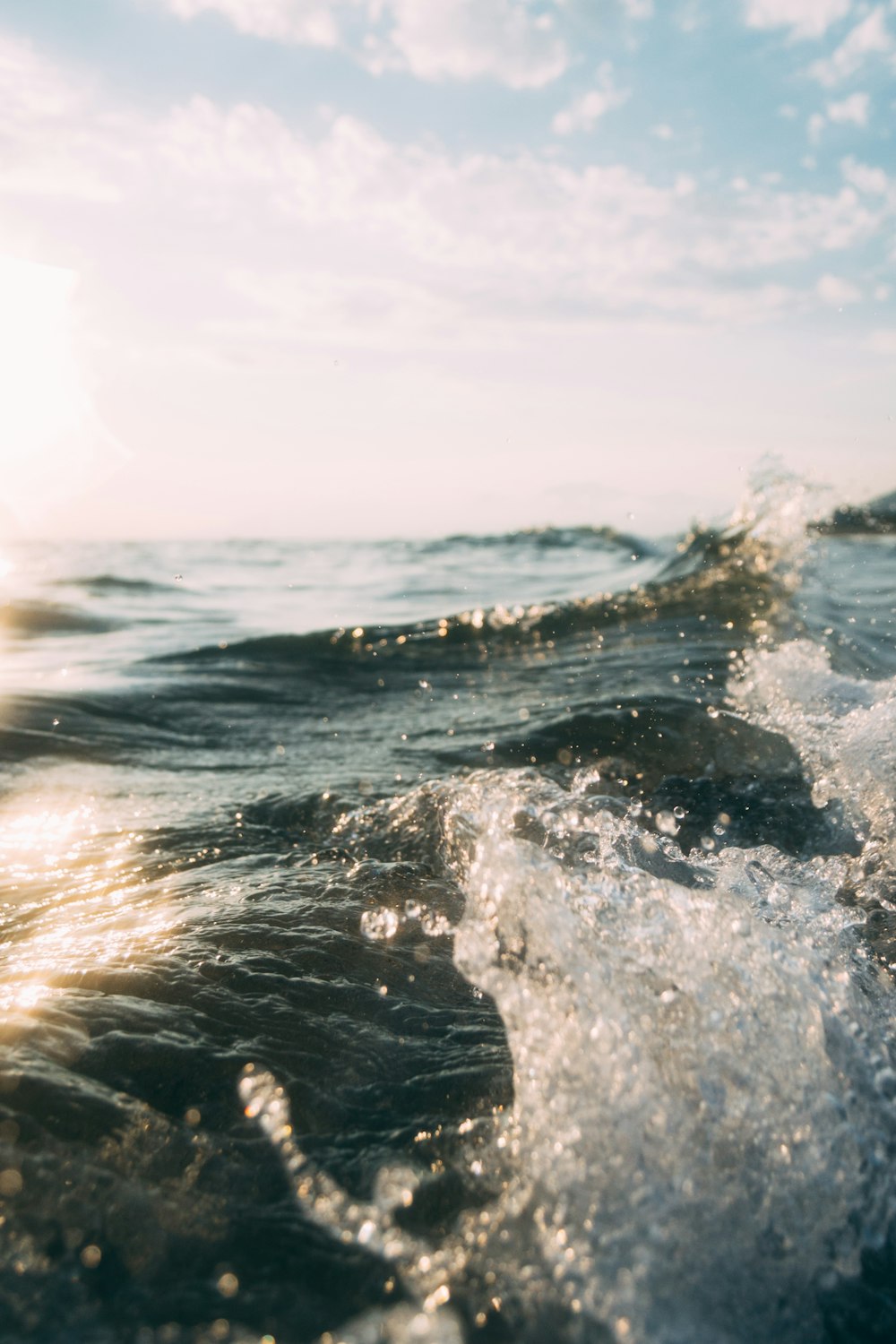 onda d'acqua sotto nuvole bianche e cielo blu durante il giorno