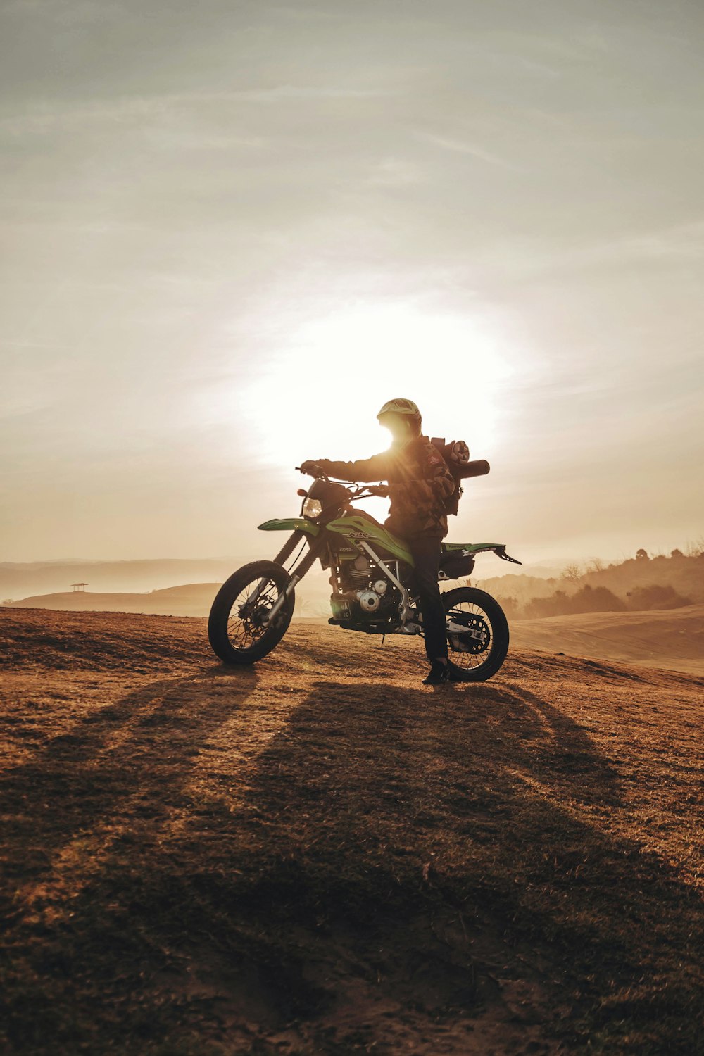 homme chevauchant une moto tout-terrain verte et noire sur un sol brun