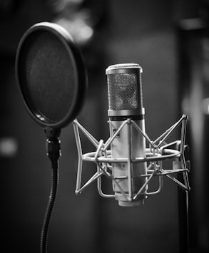 grayscale photo of condenser microphone beside pop filter