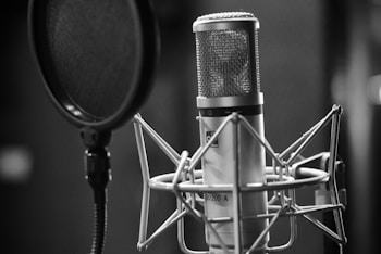 grayscale photo of condenser microphone beside pop filter