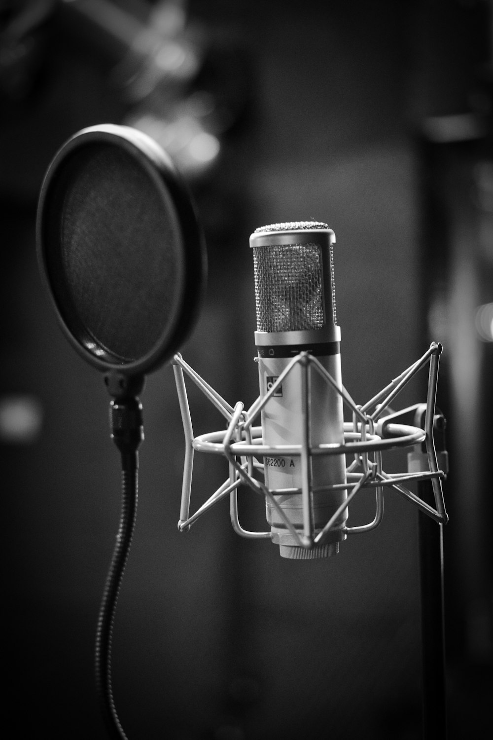 grayscale photo of condenser microphone beside pop filter