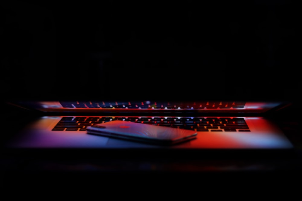 silver iPhone X on a slightly closed MacBook Pro keyboard