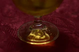Close-up of golden palm oil in a clear glass container on a wooden table.