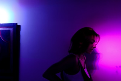 A minimalist portrait bathed in soft purple light against a dark background.