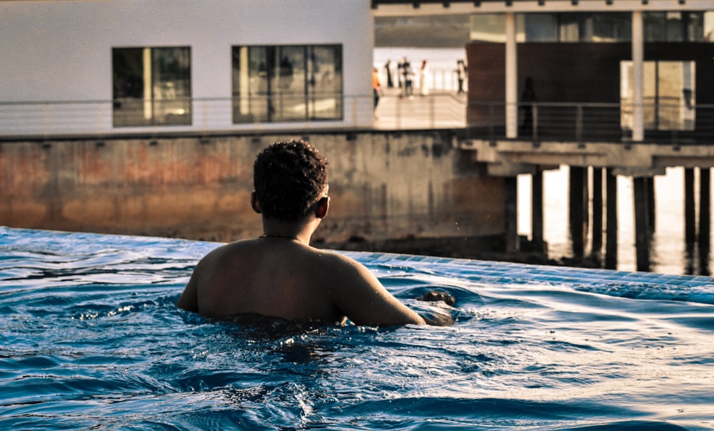 topless man swimming on pool