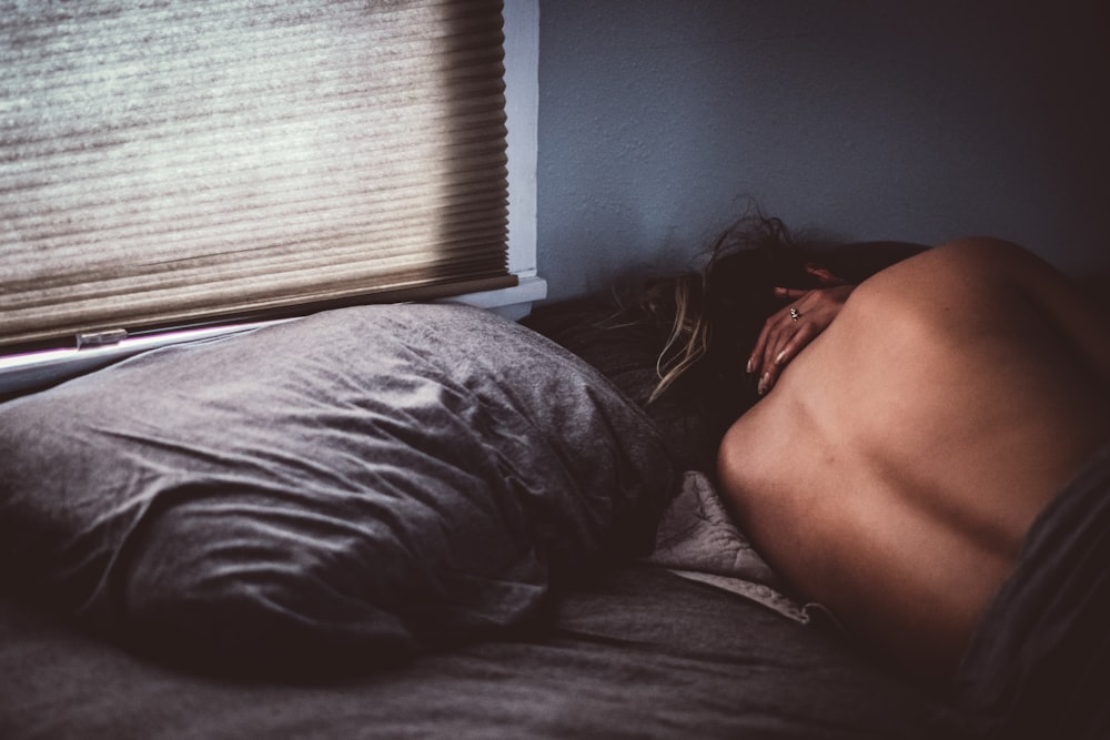 ベッドに横たわるトップレスの女性