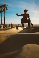 An athlete mid-air performing a trick on a skateboard at a sunny skatepark.