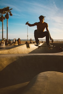 An athlete mid-air performing a trick on a skateboard at a sunny skatepark.