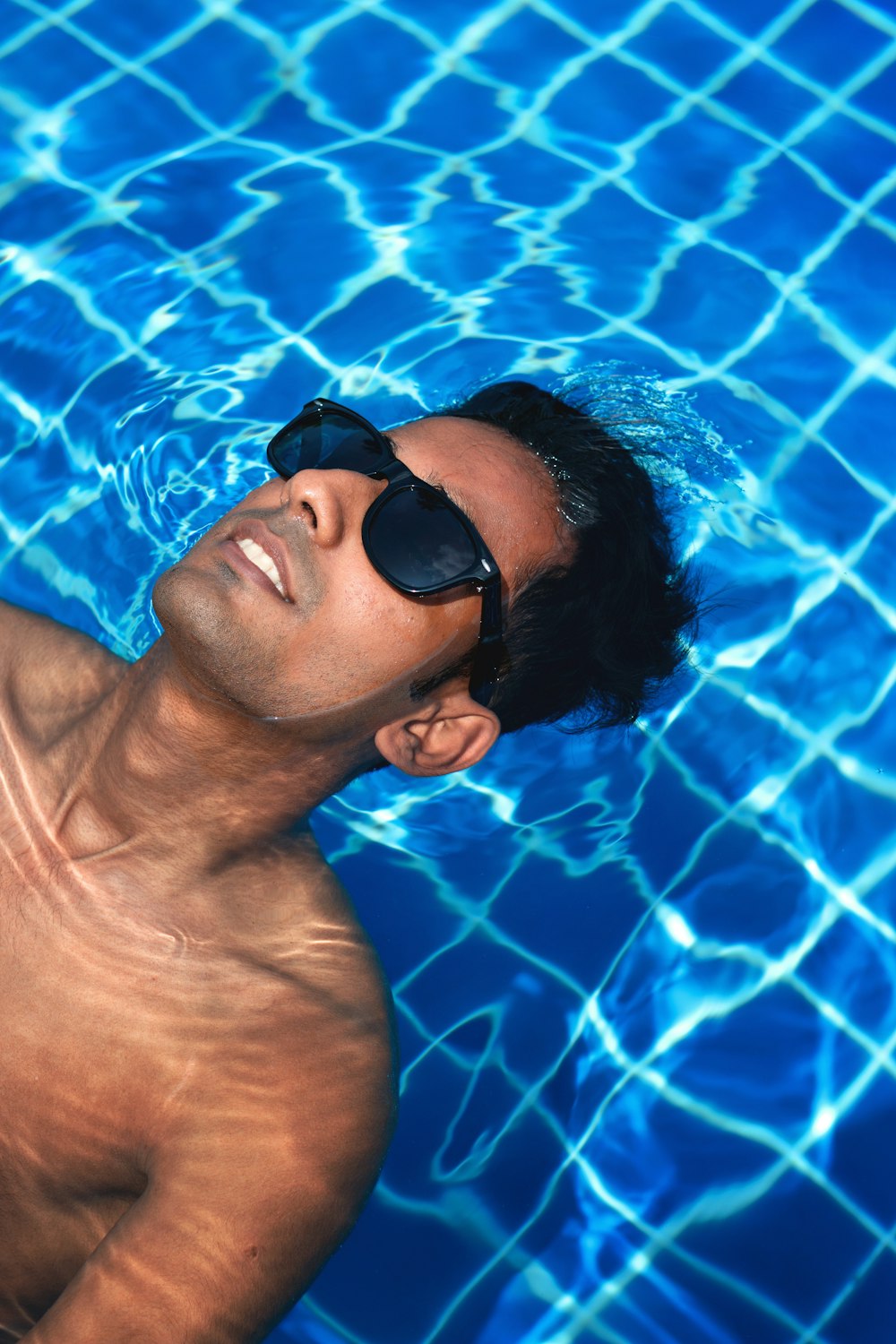 man wearing black framed sunglasses floating on body of water
