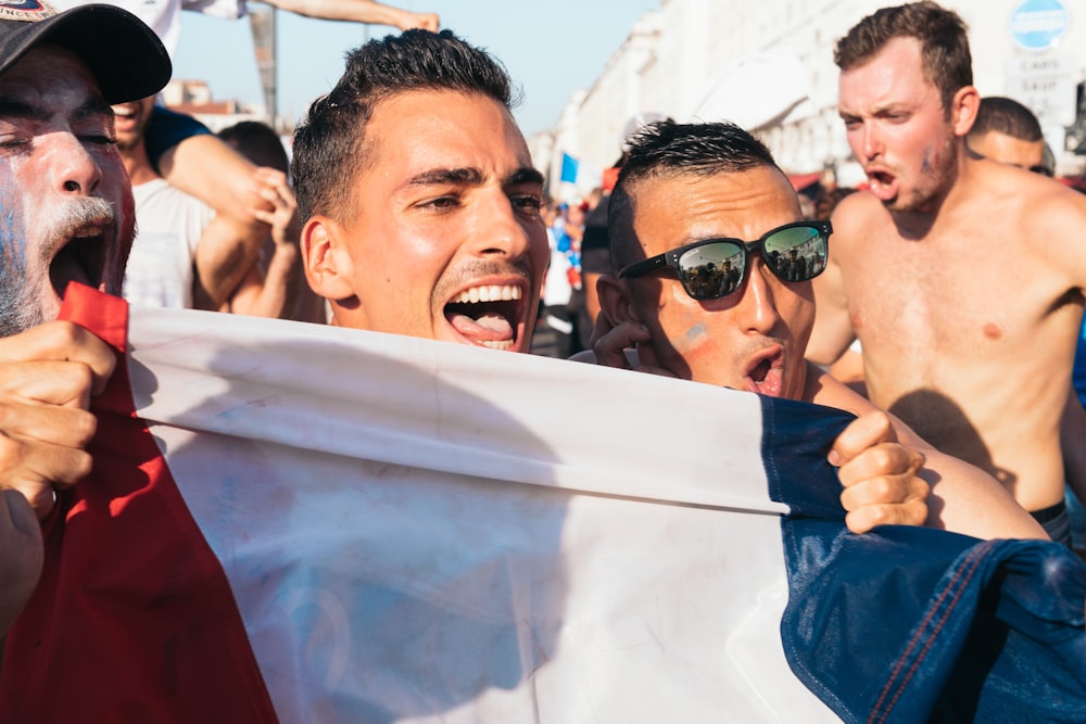 Hombres sosteniendo la bandera cerca de la gente durante el día