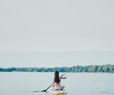 woman sitting on yellow paddle board during daytime
