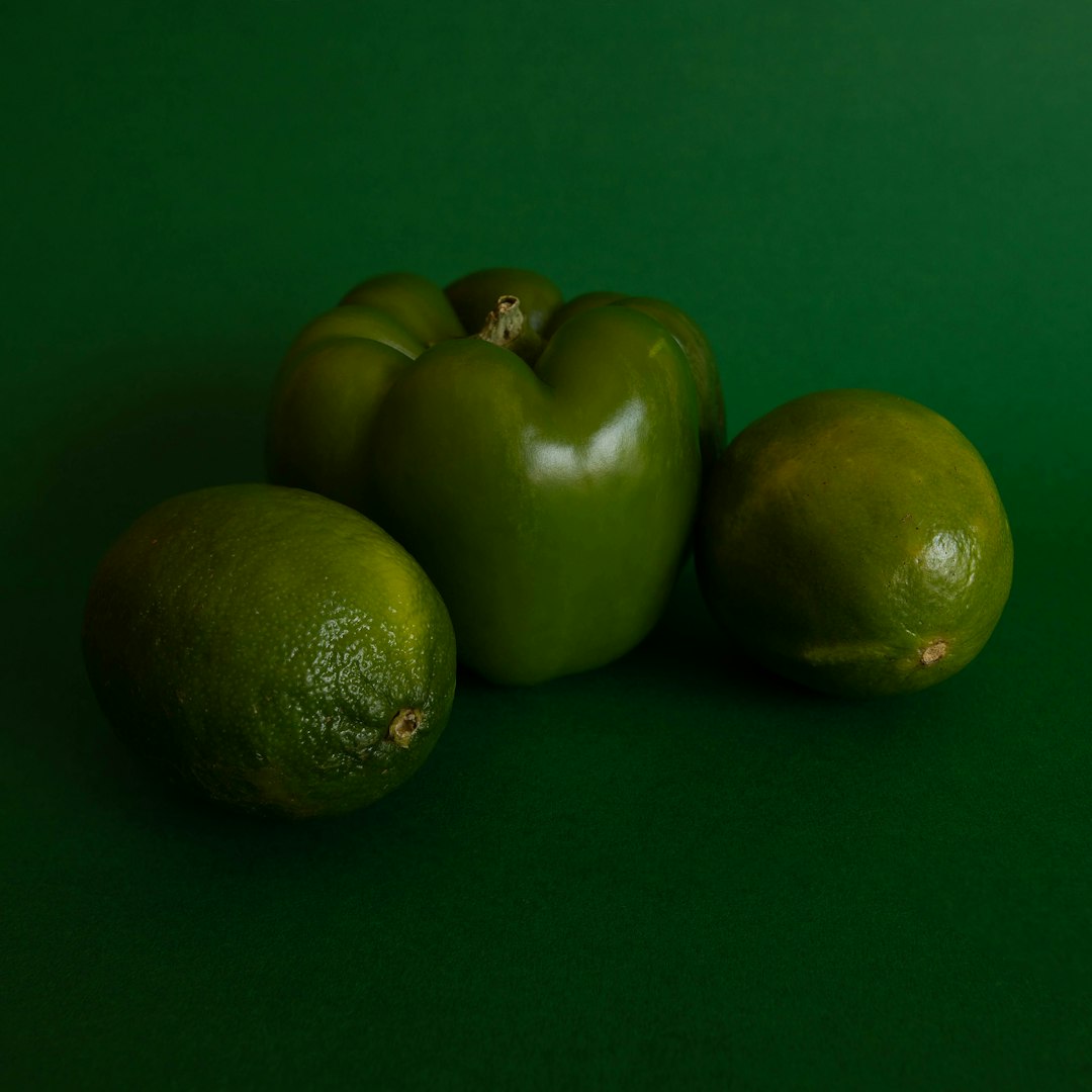 chili pepper and green fruit on green surface