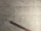 A cracked, pale, tiled floor with a prominent diagonal crack running across the surface. A dark brown wooden bannister is positioned at the bottom left corner, casting a shadow on the floor.