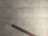 A cracked, pale, tiled floor with a prominent diagonal crack running across the surface. A dark brown wooden bannister is positioned at the bottom left corner, casting a shadow on the floor.