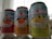 Three cans of Sanpellegrino sparkling beverages are placed side by side, each labeled with different fruit flavors: blood orange, orange, and grapefruit. The design features bright, colorful images of the corresponding fruits with a star logo above the brand name. The cans have details about the juice content and other natural flavors.
