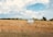 An old pickup truck parked beside a potato field under a clear blue Idaho sky.