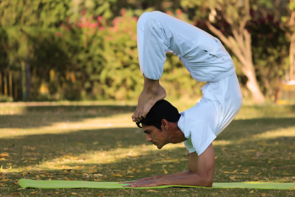 man acrobating on green pad during daytime