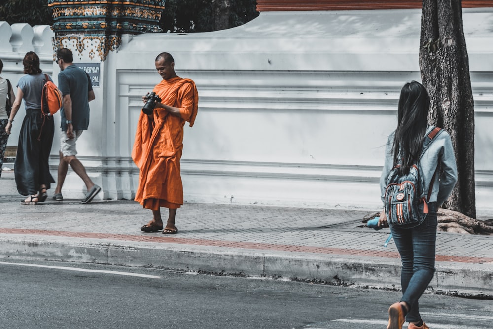 monk holding black DSLR camera while smiling