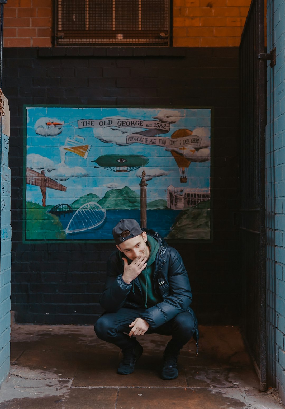 man squatting in front of wall graffiti