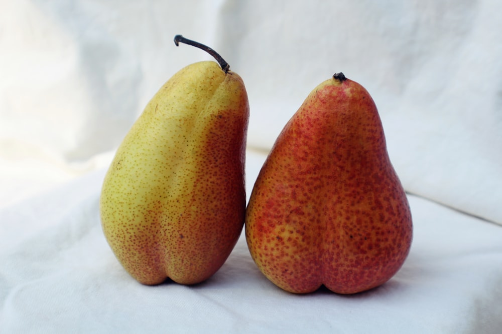two yellow pears on white textile
