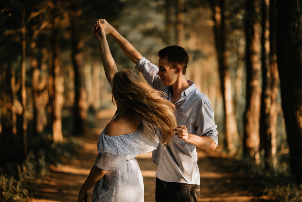 uomo e donna che ballano al centro degli alberi