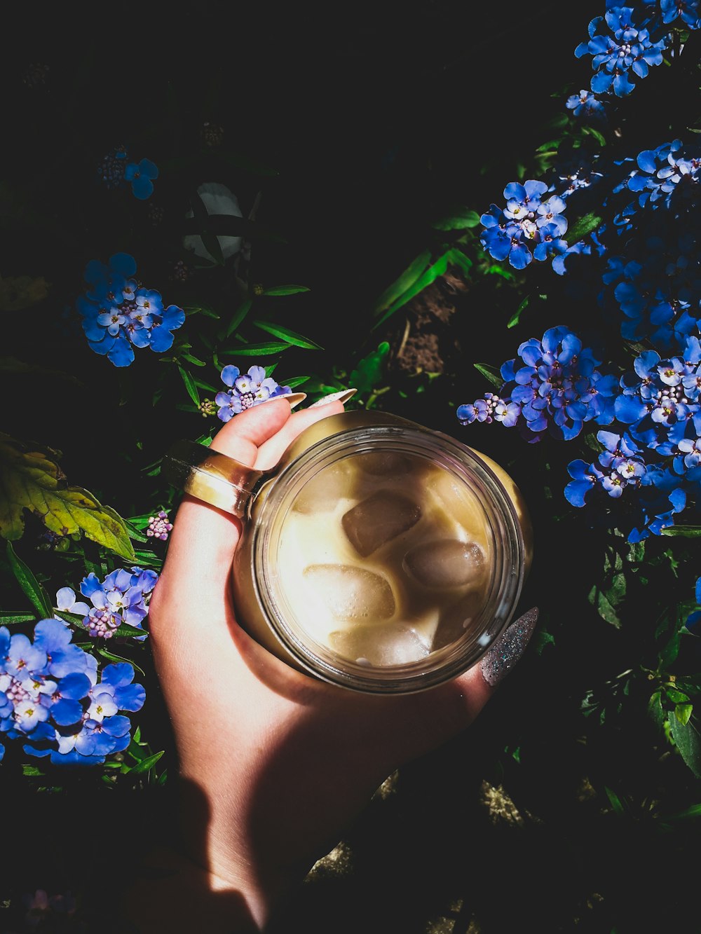 person holding clear mug filled with liquid and ice