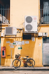 red and black bike beside yellow wall