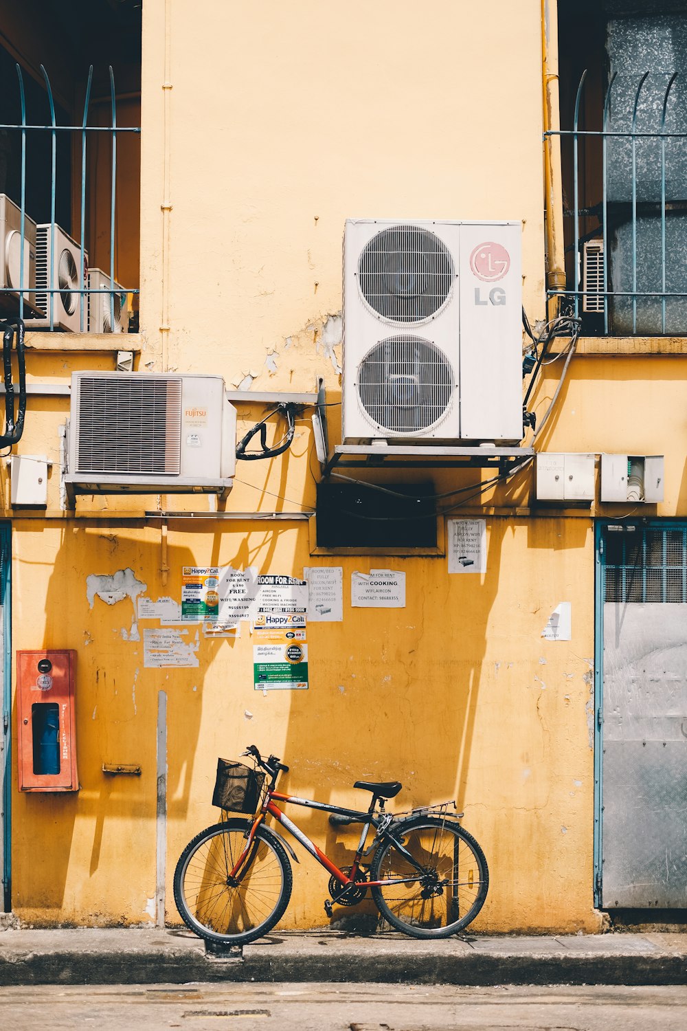 bicicleta vermelha e preta ao lado da parede amarela