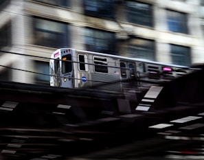 An RRTS train speeding along elevated tracks with city buildings in the background.