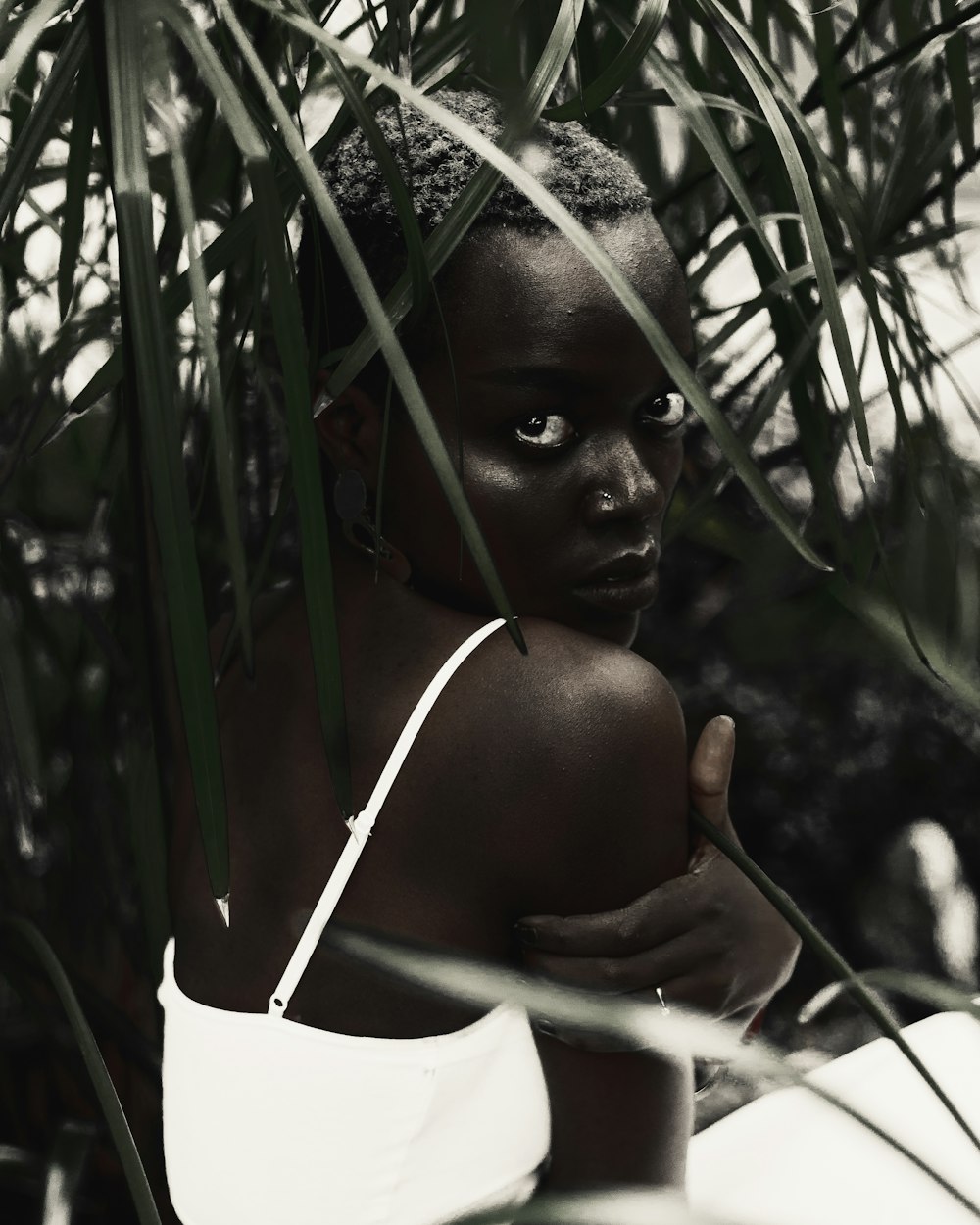 a woman in a white dress standing under a palm tree