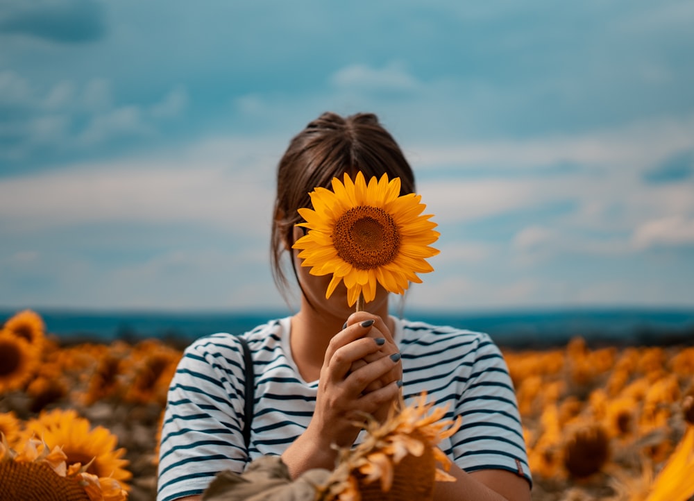 mujer sosteniendo un girasol amarillo