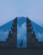 woman in between on concrete landmarks near white clouds