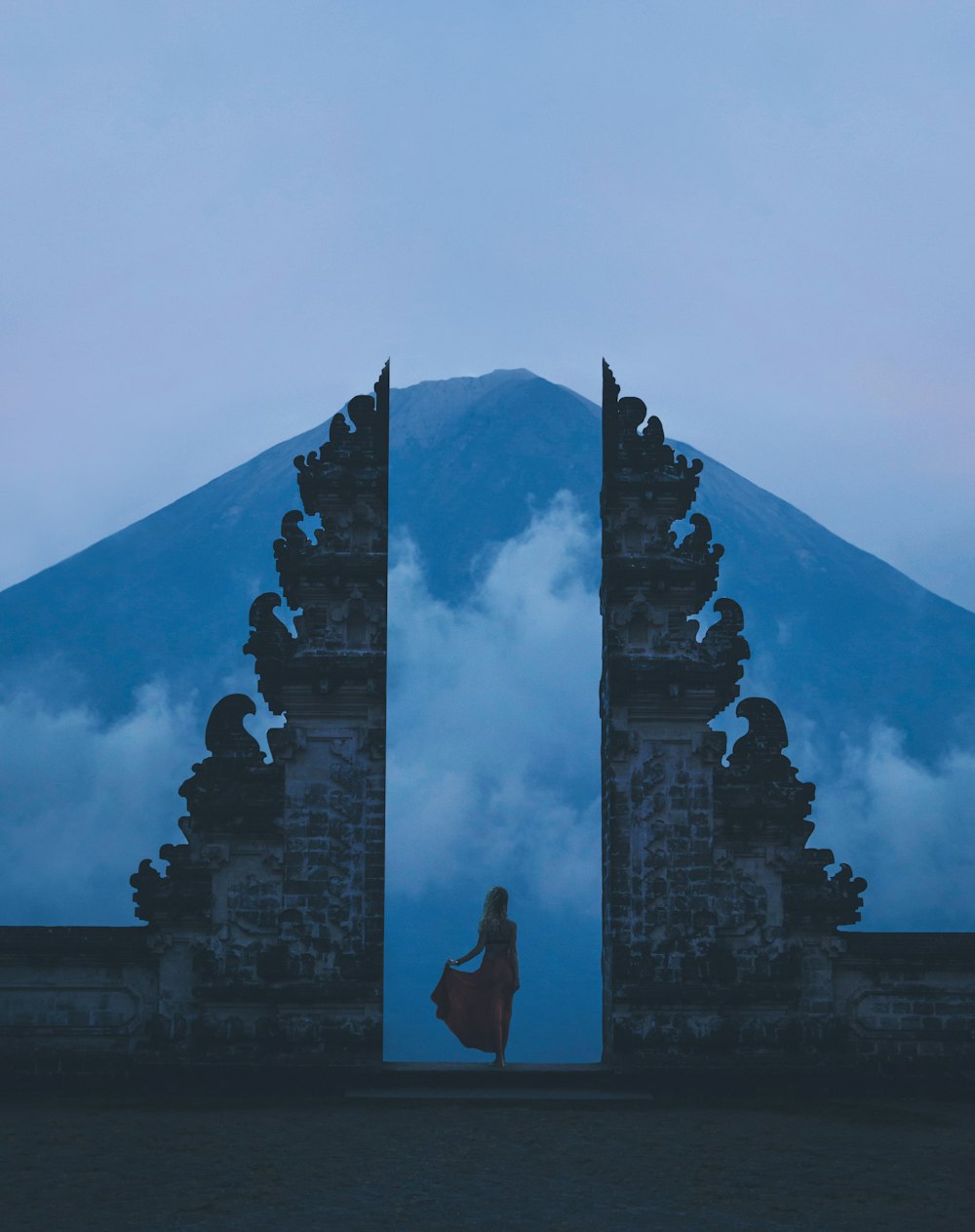 woman in between on concrete landmarks near white clouds