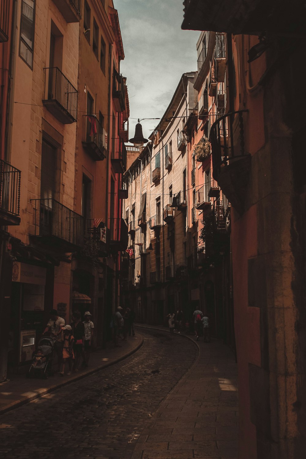 Pessoas andando na rua ao lado do prédio marrom