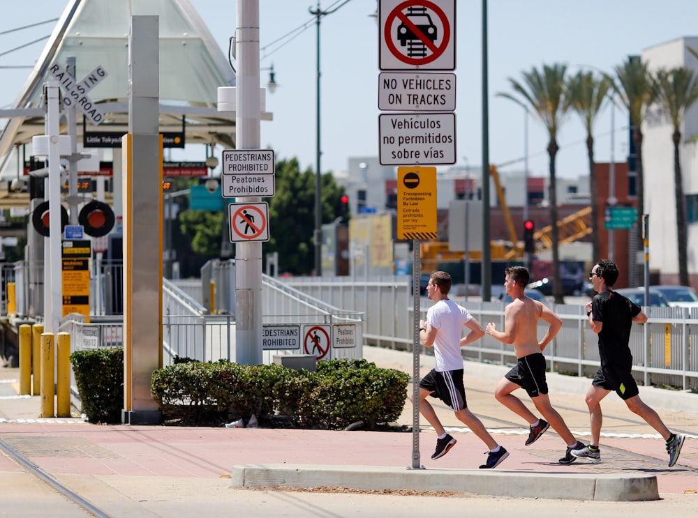 three men running beside signage