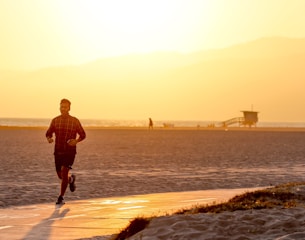 A small group jogging lightly along a beach path during golden hour, with relaxed, encouraging expressions.