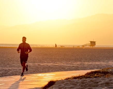 A small group jogging lightly along a beach path during golden hour, with relaxed, encouraging expressions.