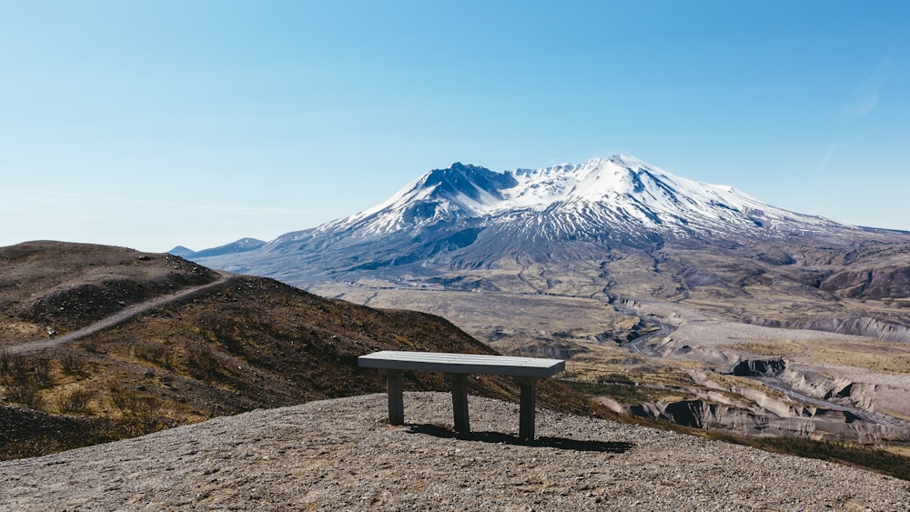 banc sur sol gris près des montagnes