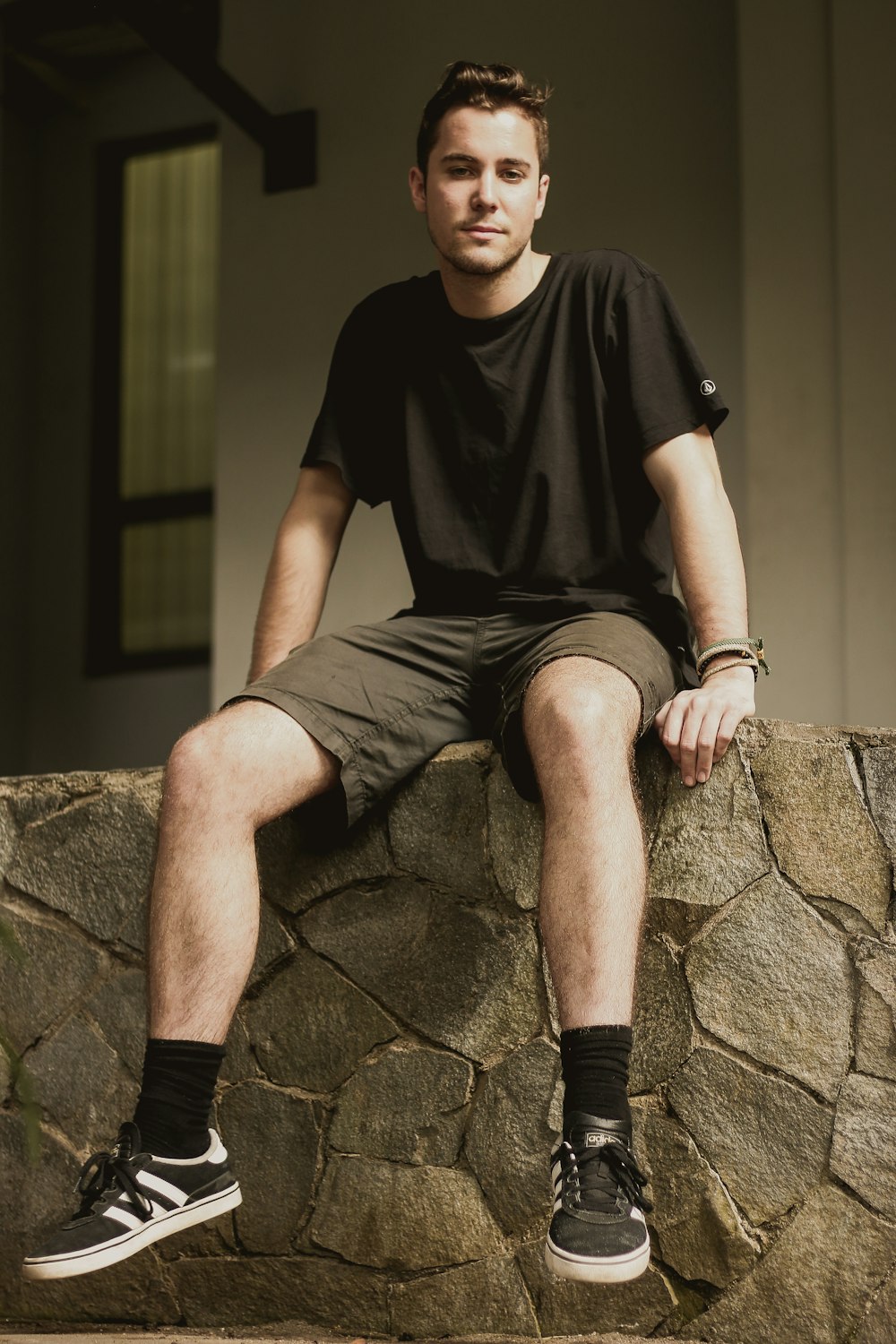 man wearing black crew-neck shirt sitting on concrete floor