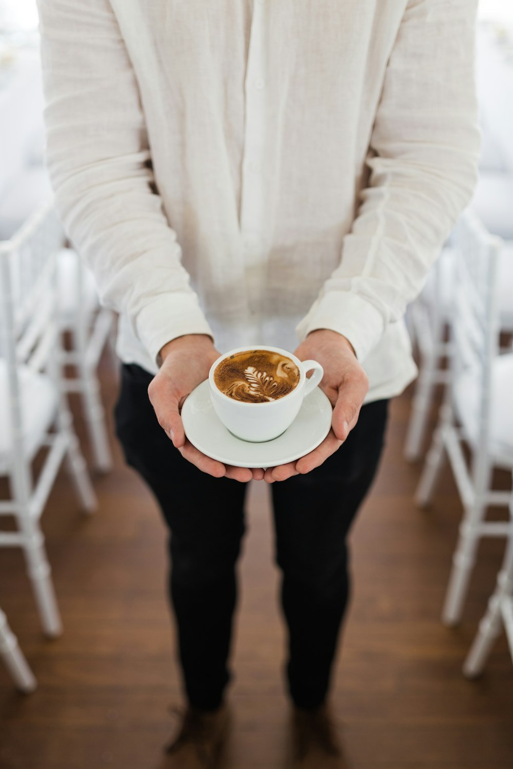 person holding coffee near dining tables