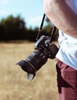 person holding camera standing on grass