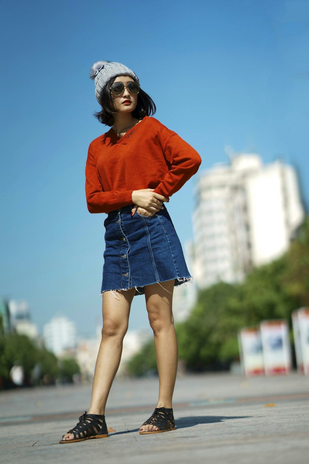 Mise au point sélective d’une femme portant une chemise à manches longues rouge et une jupe en jean bleue debout sur la route