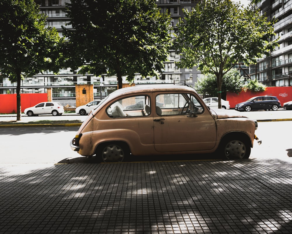 brown 3-door hatchback parked near road gutter