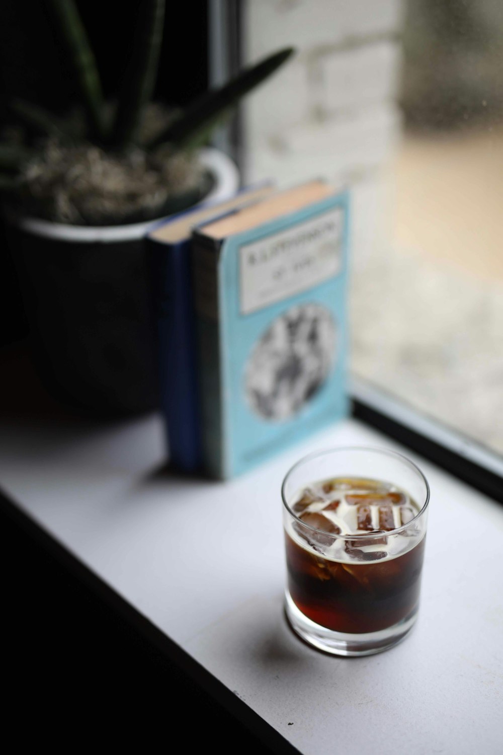 clear drinking glass beside book and plant