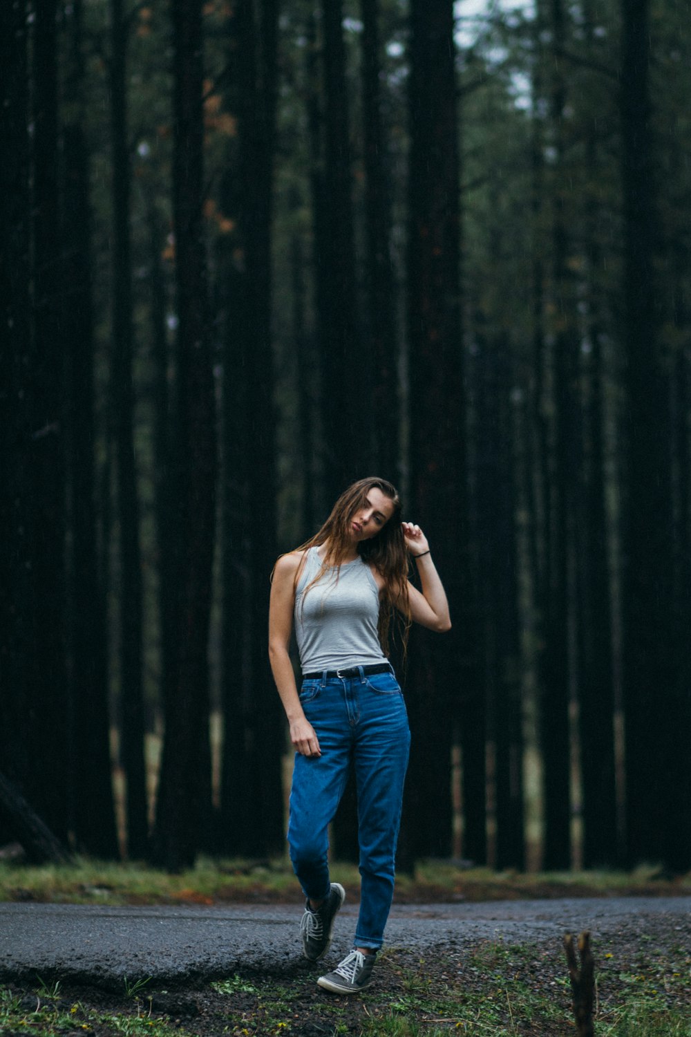 donna in piedi sulla passerella davanti agli alberi della foresta