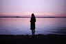 woman standing near body of water during golden hour